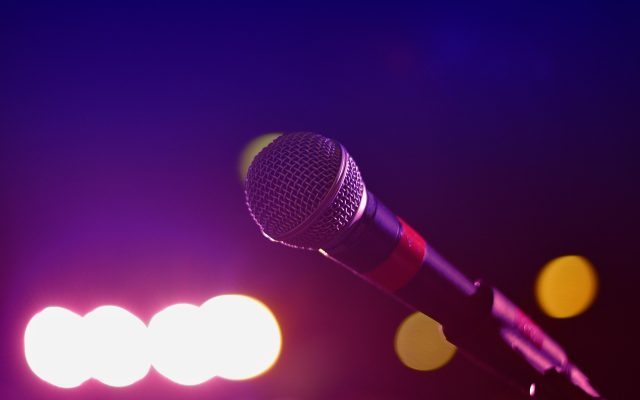 综艺演播厅舞台灯光下主持人站位区域，暖橙色聚光灯打在舞台中央，氛围明亮热闹
